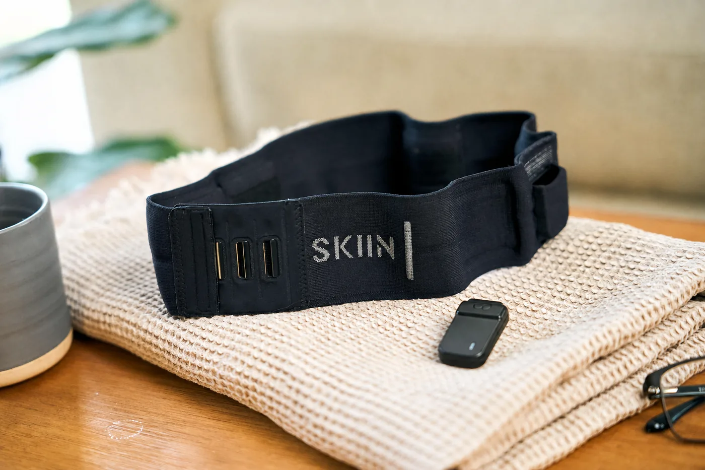 The SKIIN™ band and its pod resting on a folded towel